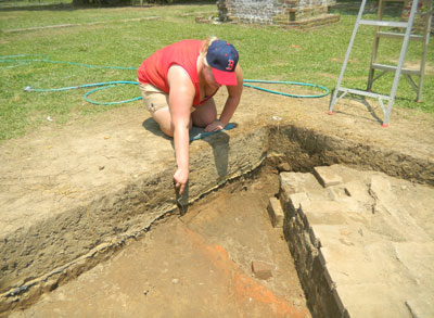 Alice Mutter points to the corner of the burned clay cellar adjacent to the brick foundation of the 1840s smokehouse.