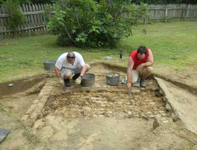 Rob Crook and John Young remove the bricks of the 1840s smokehouse floor.