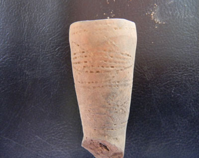 Terra cotta pipe with incised decorations of fish.